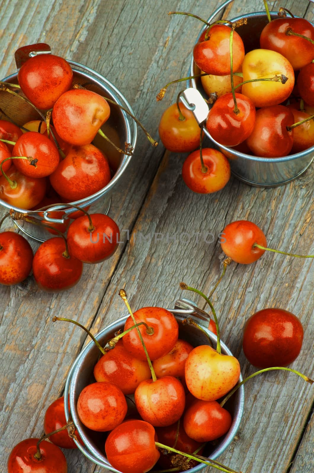 Three Tin Buckets Full of Sweet Maraschino Cherries on Rustic Wooden background. Top View