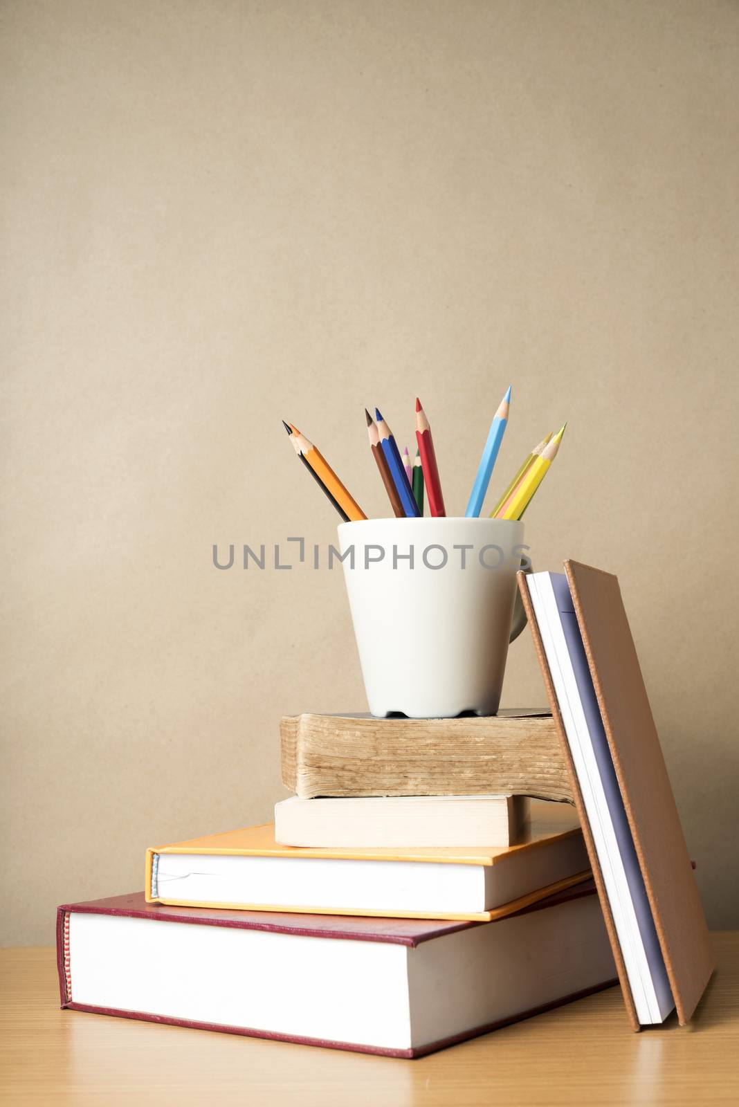 stack of book with color pencil on wood table background