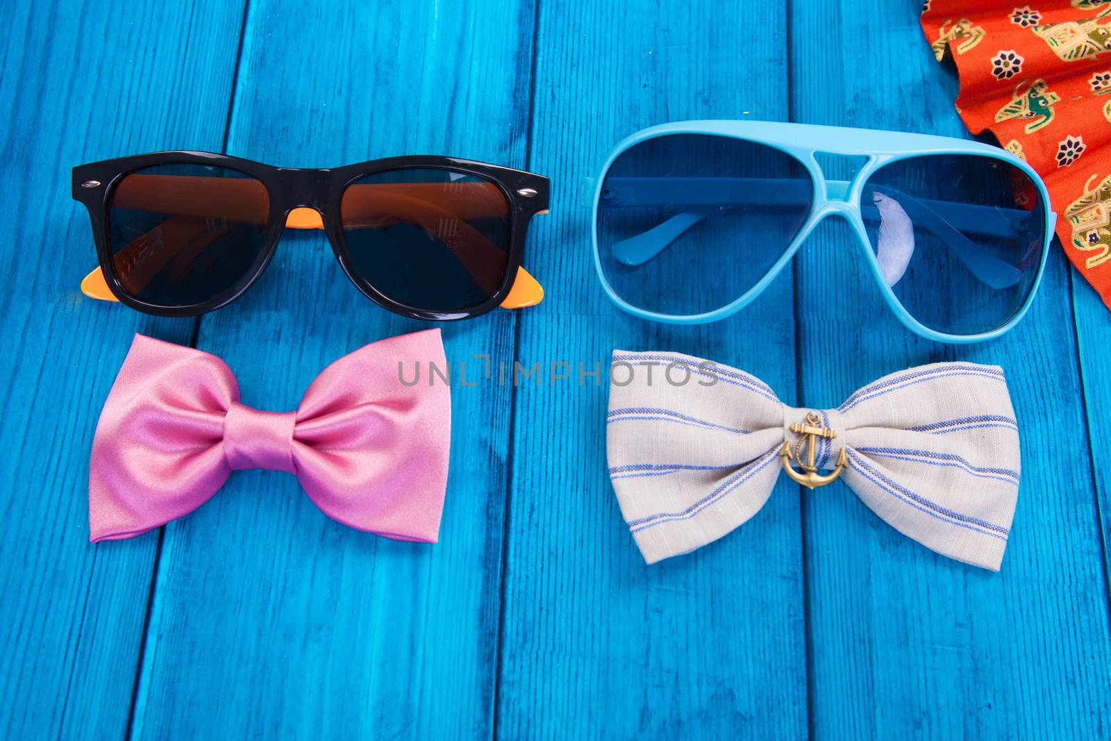 fan with red bow tie and sunglasses on blue wooden background