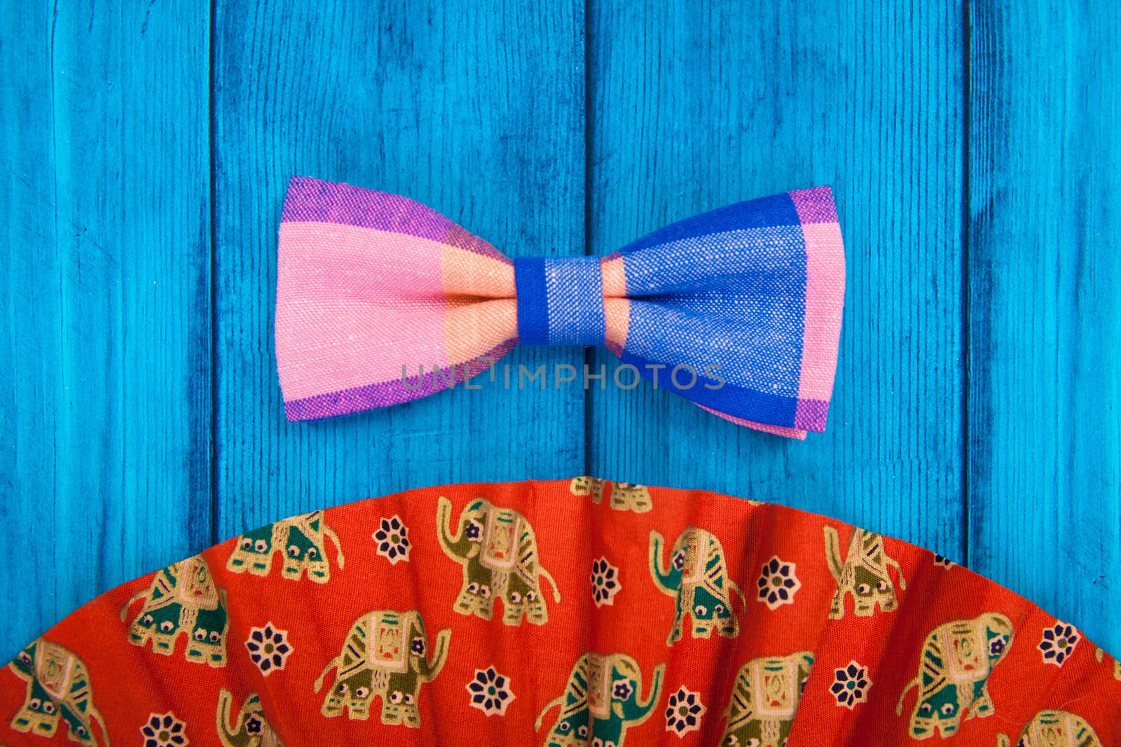 fan with red bow tie on blue wooden background