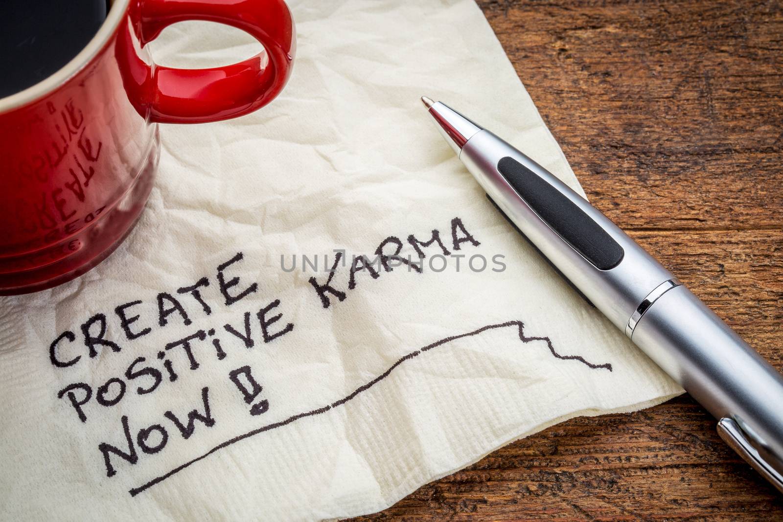 create positive karma now - motivational handwriting on a napkin with cup of coffee