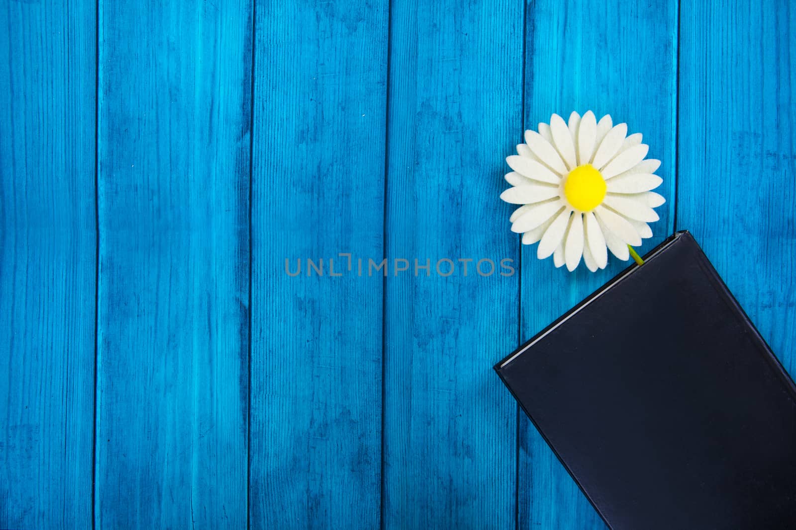 tab in the diary in the form of a flower on a blue wooden background