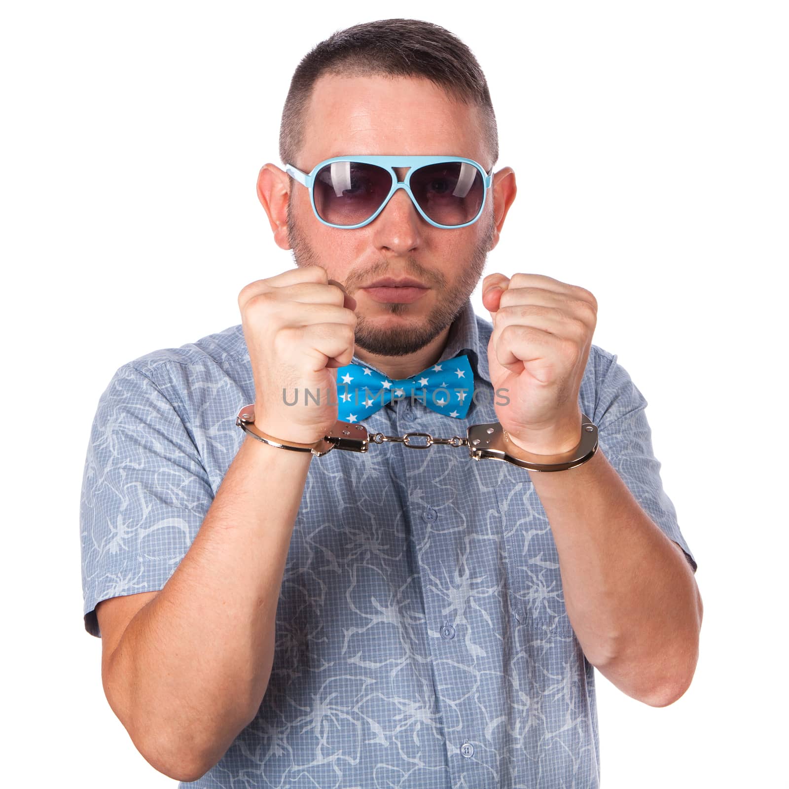 Adult male with beard in a blue bow tie in summer shirt in police handcuffs isolated on a white background