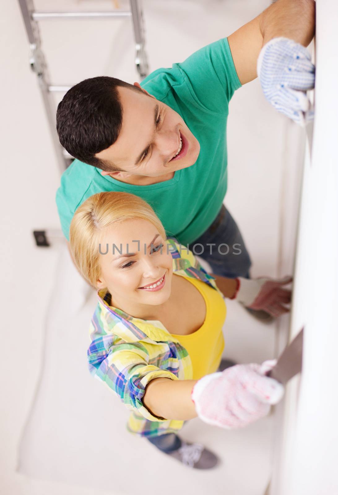 smiling couple doing renovations at home by dolgachov