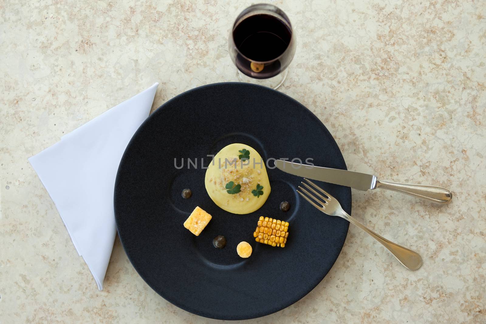 Egg, corn, polenta and black olive on a plate