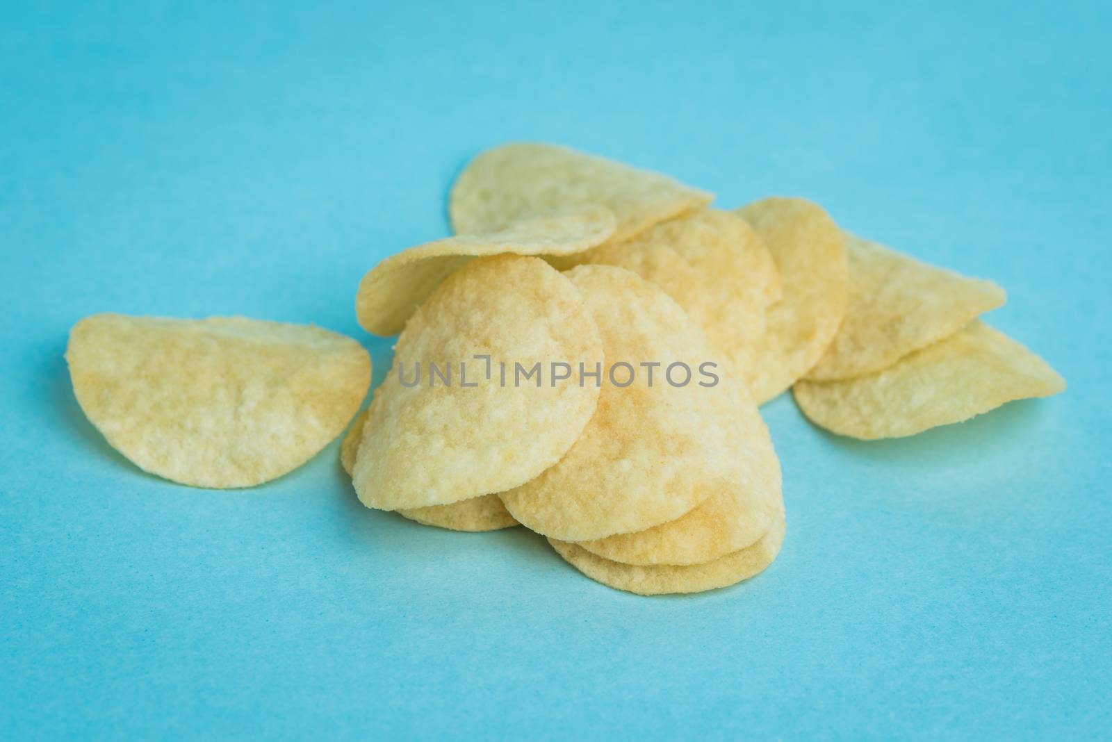 A macro shot of mini potato chips on a blue background.