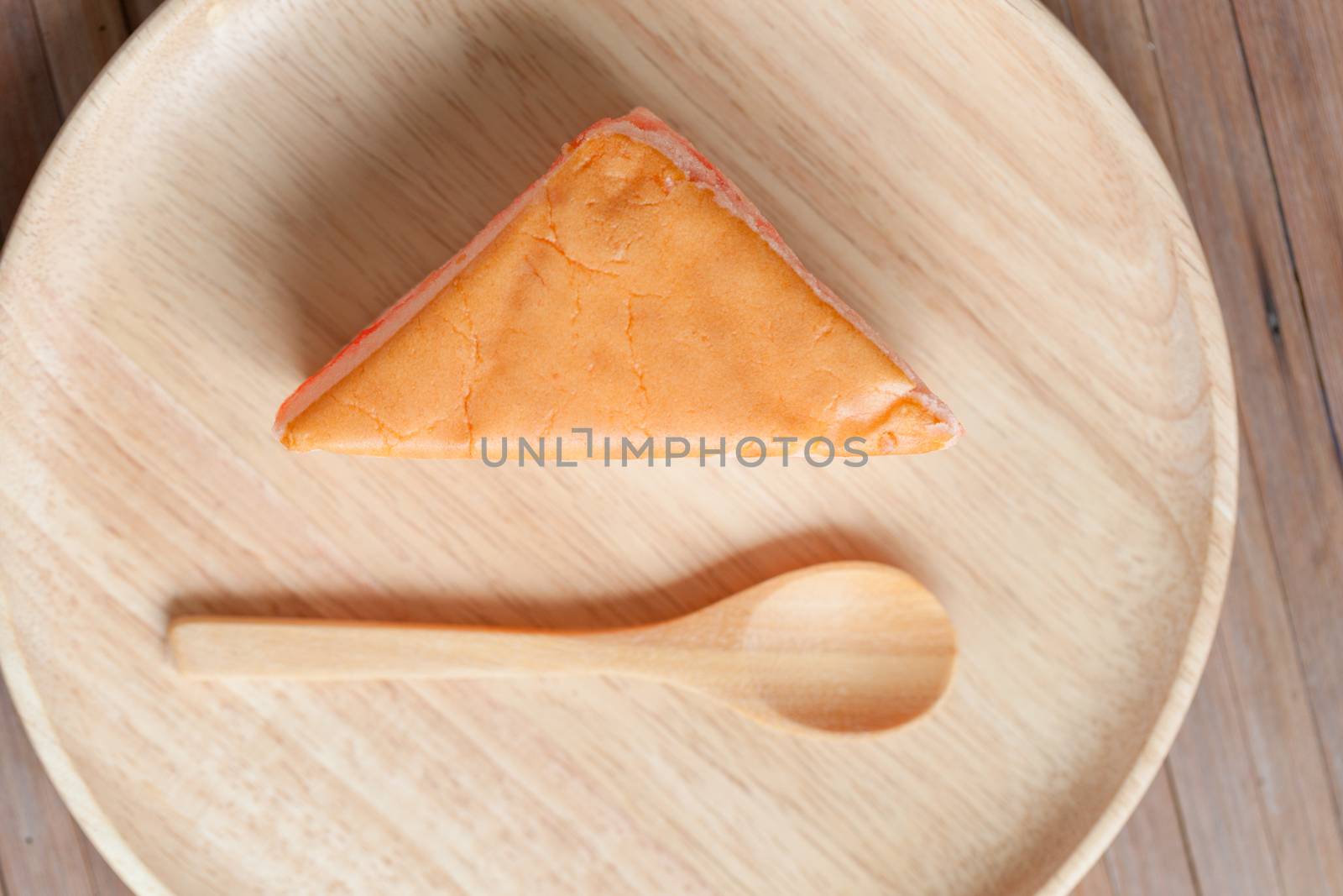 Orange cake placed in wooden plates on the table. With wooden spoon