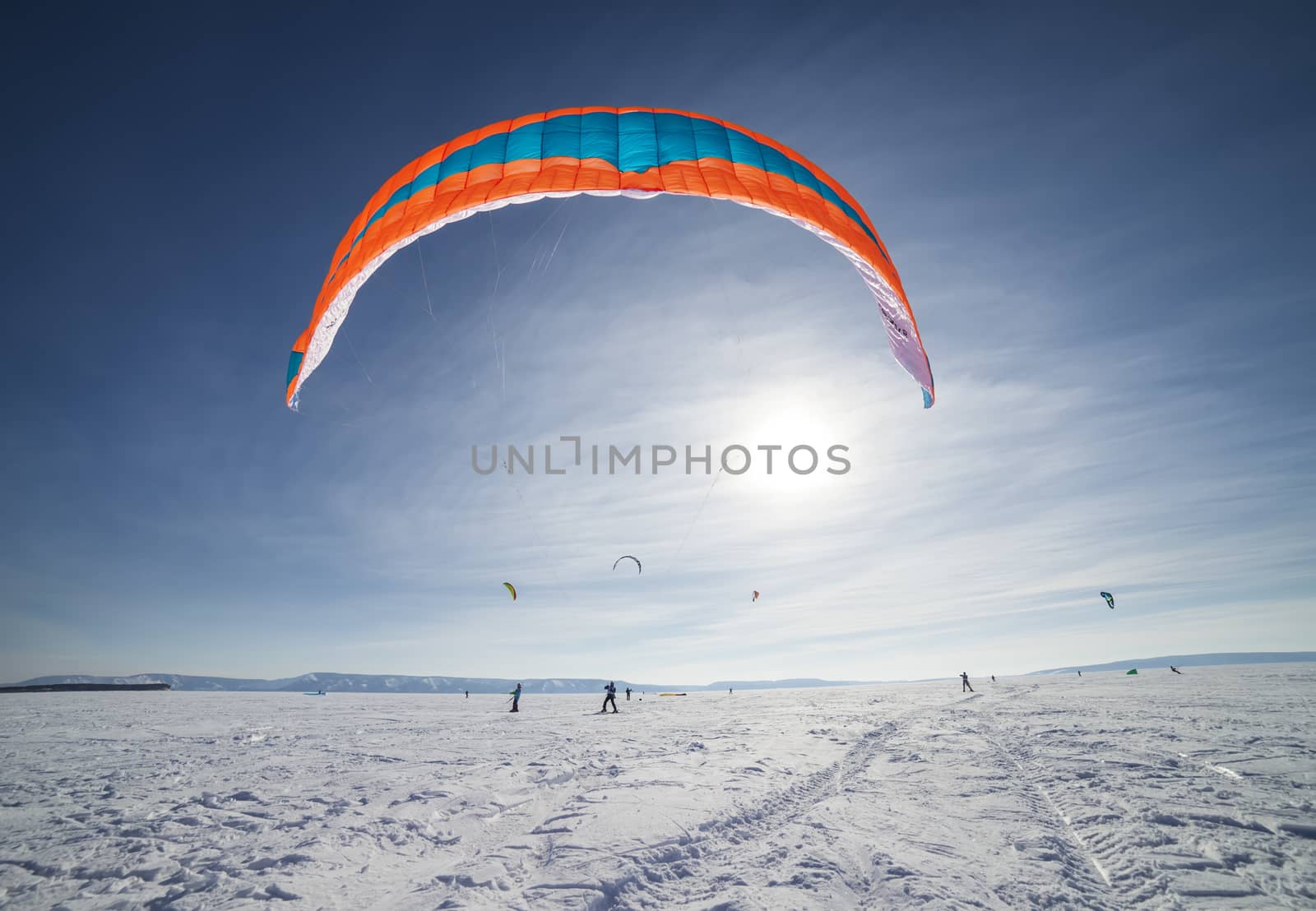 Kite surfer being pulled by his kite across the snow