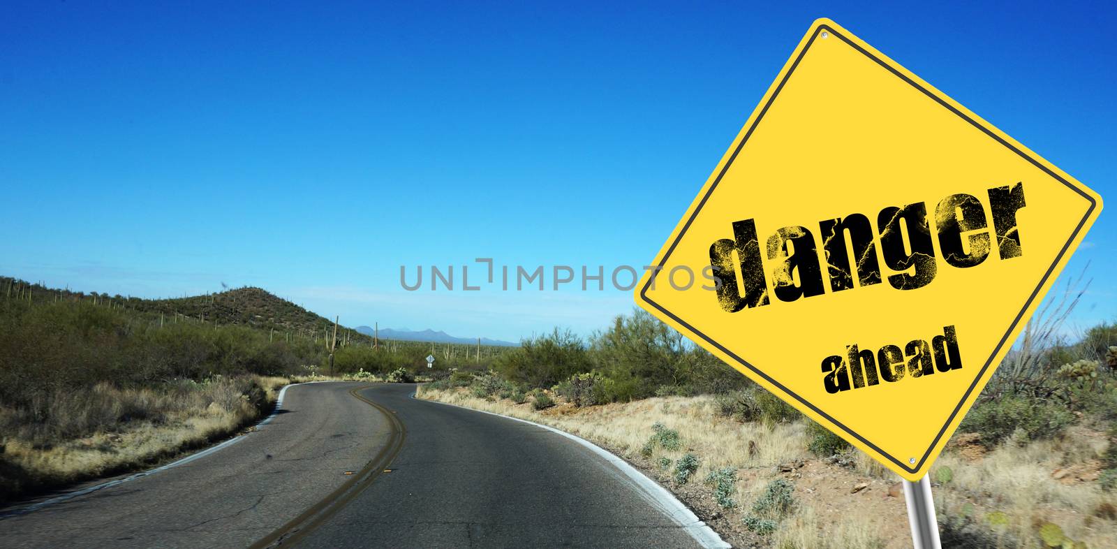 Danger ahead sign on a sky background and dessert road