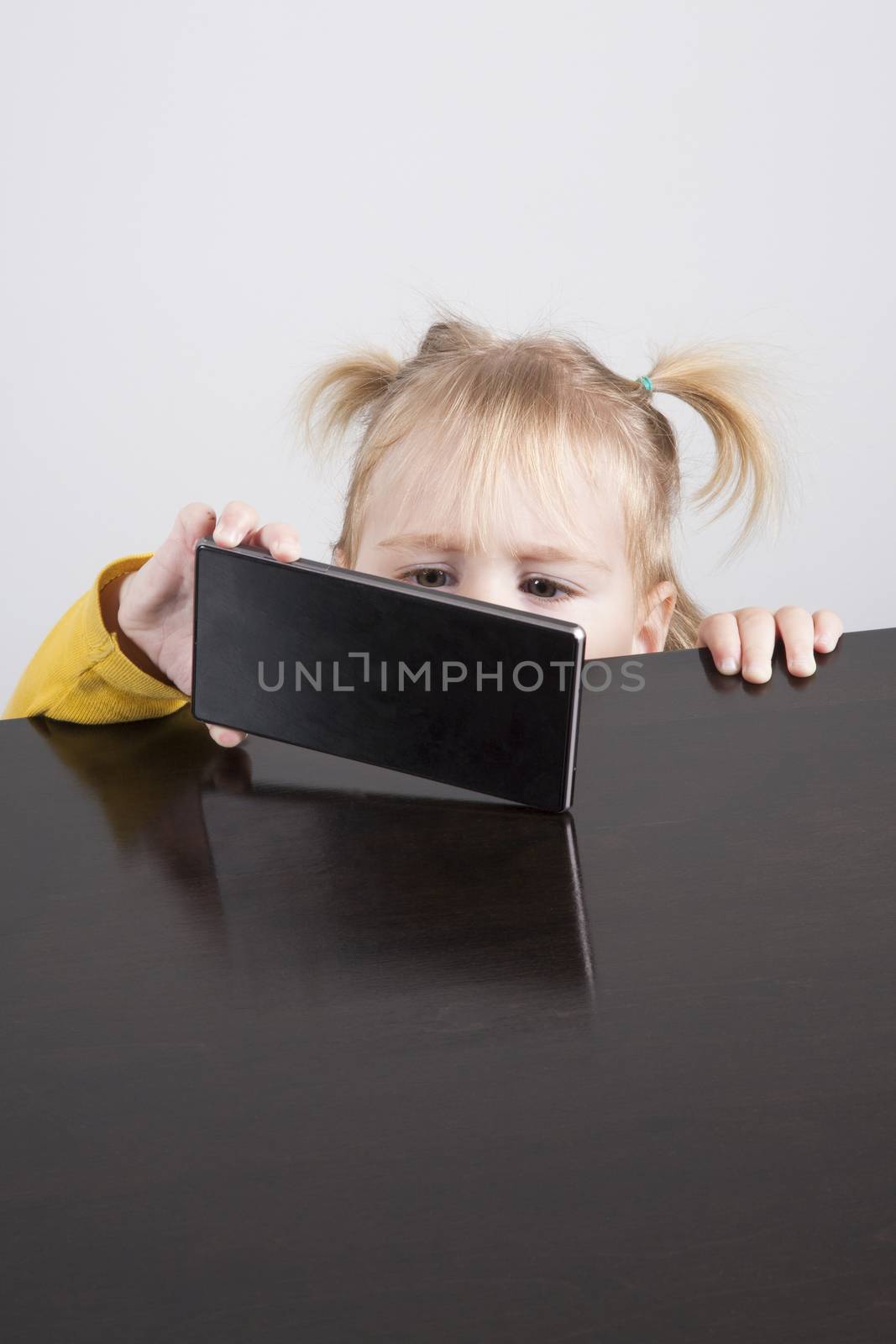 baby watching phone on table by quintanilla