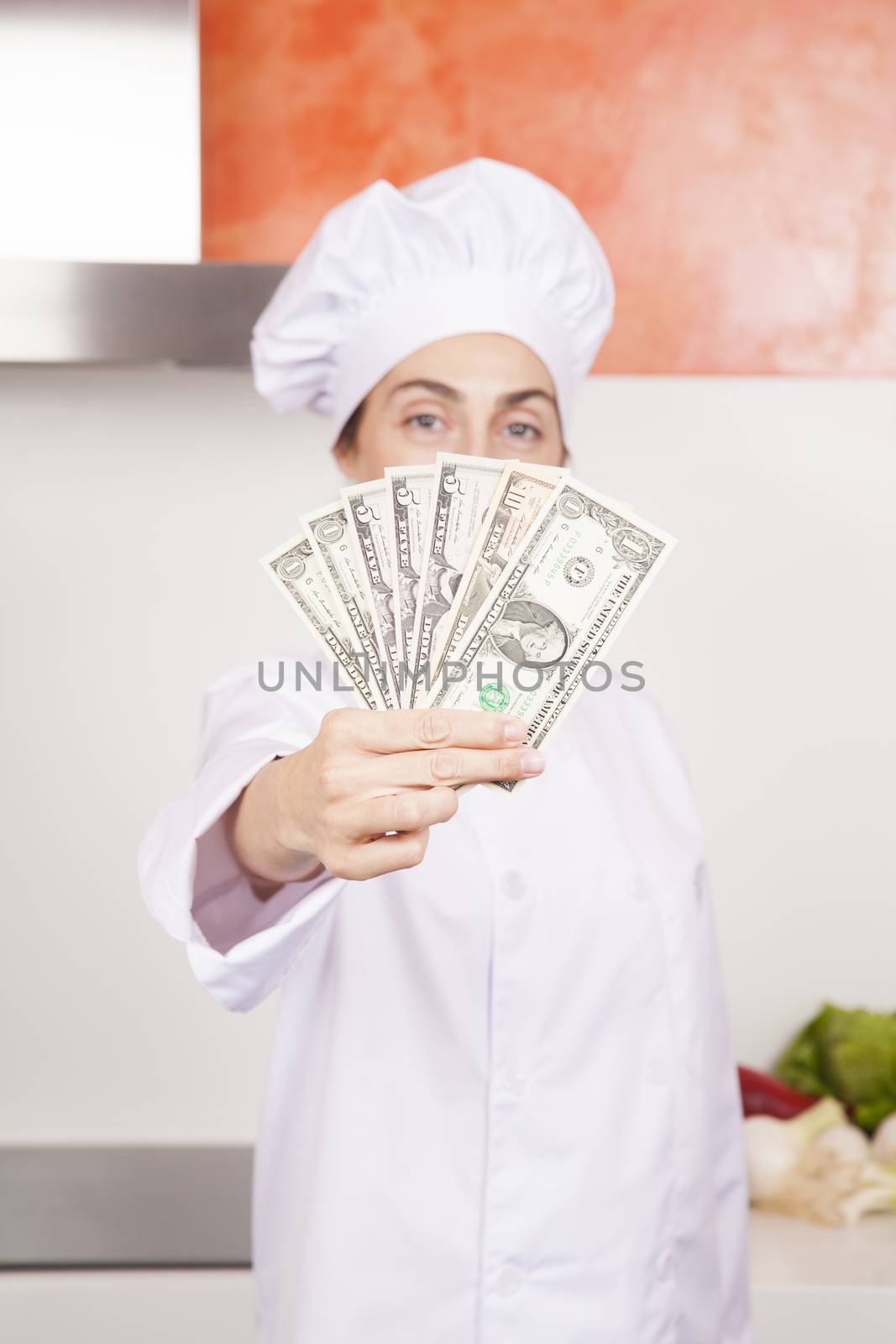 wad of dollar banknotes in woman chef hand by quintanilla