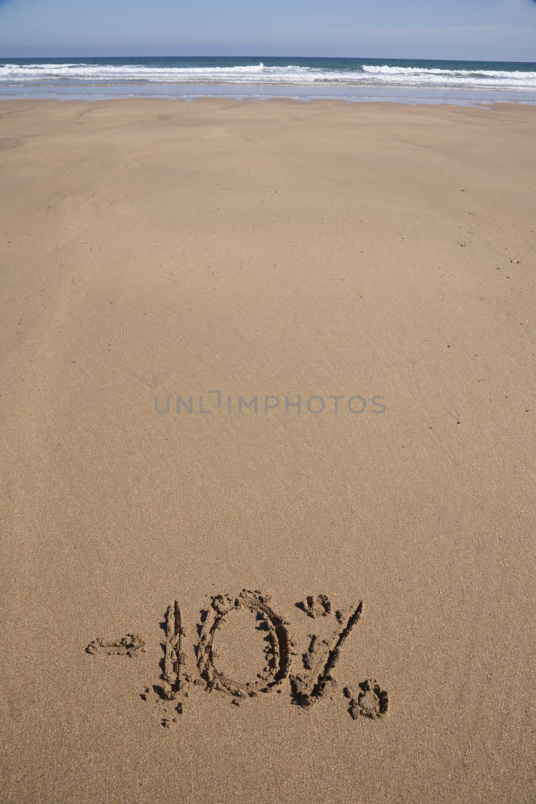 10 percent discount in earth text written on brown sand ground low tide beach ocean seashore in Spain Europe