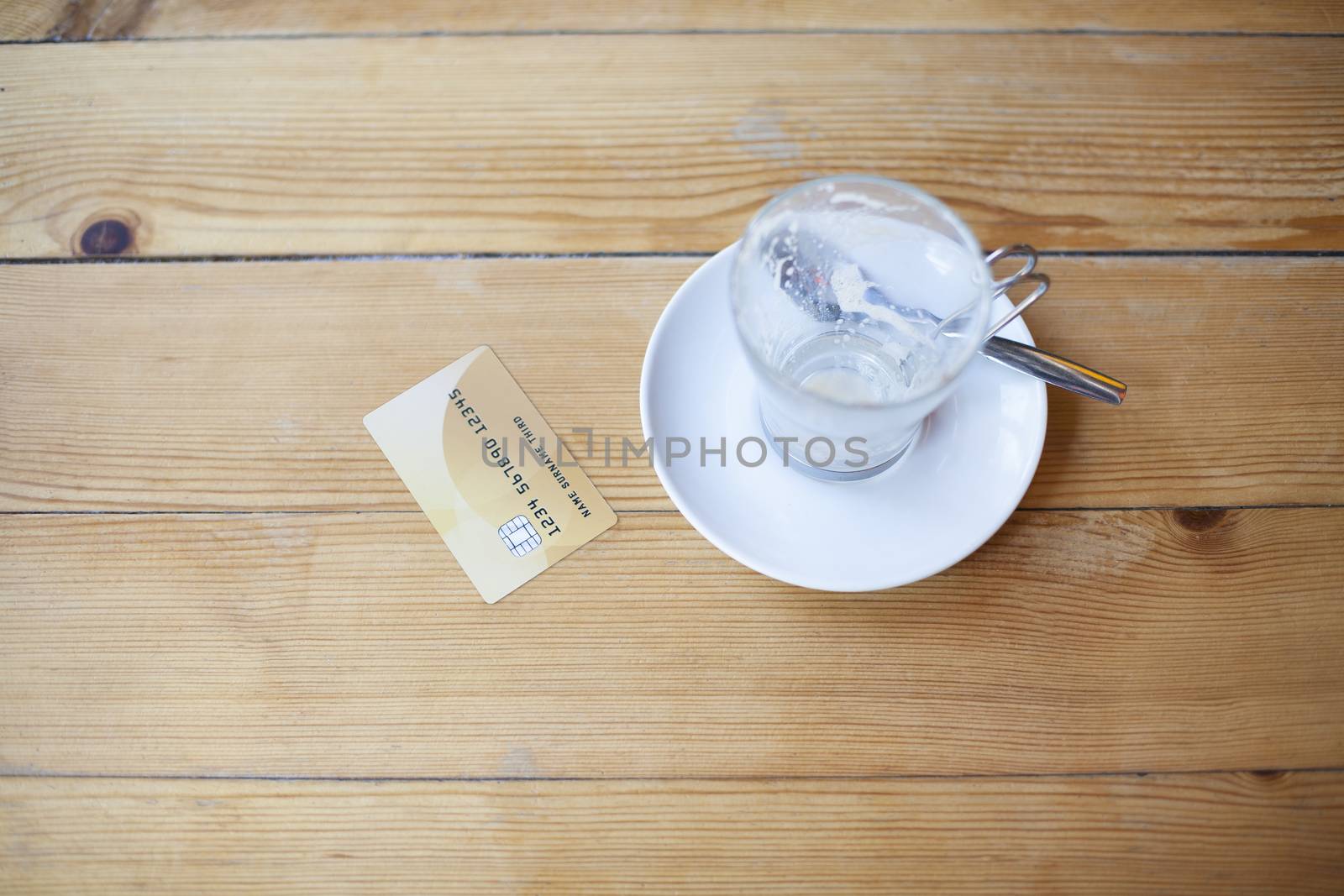 made up credit card ready to pay empty finished cappuccino coffee cup on light brown wooden table cafe