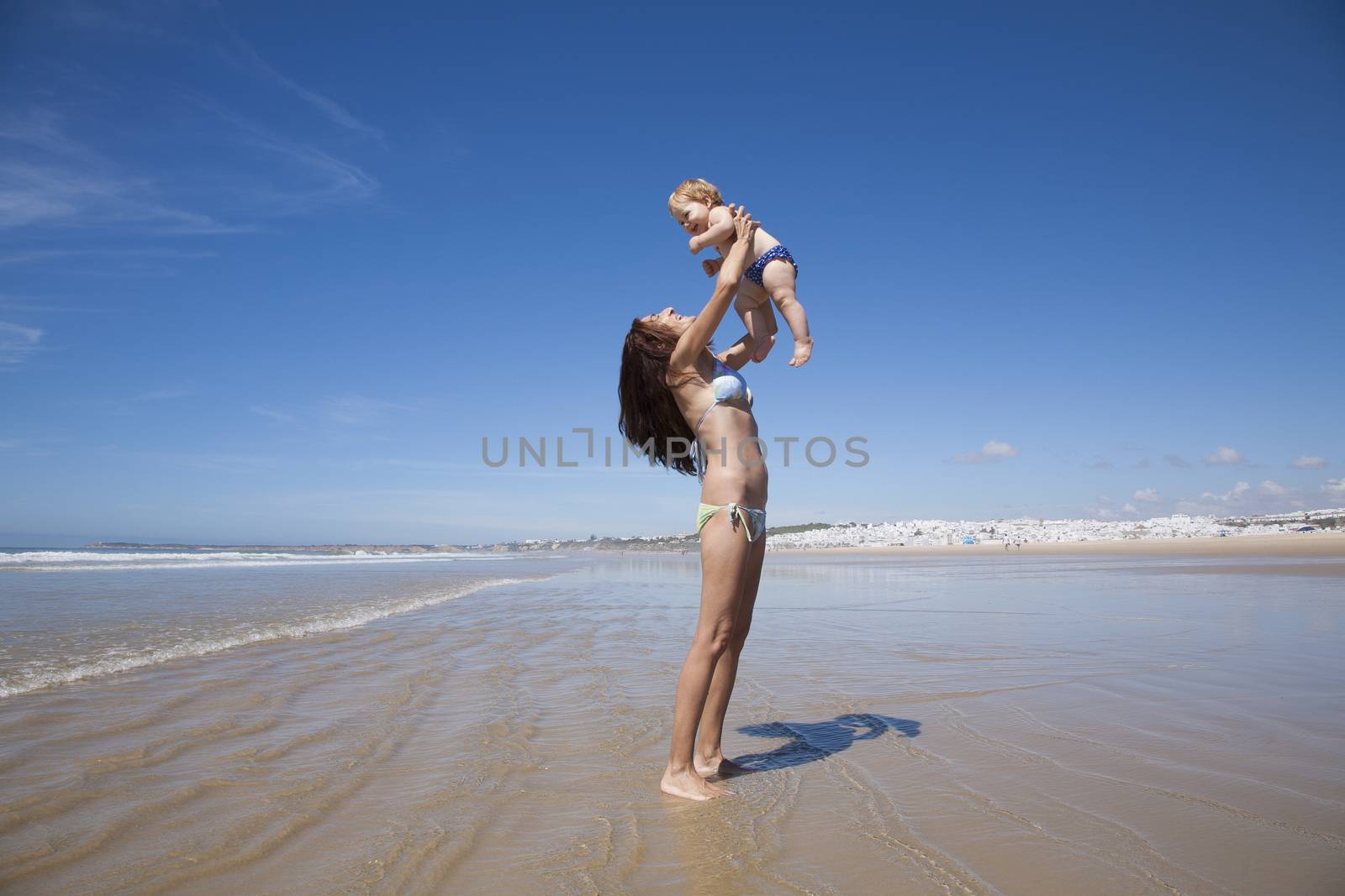 baby flying in woman arms next to Conil by quintanilla
