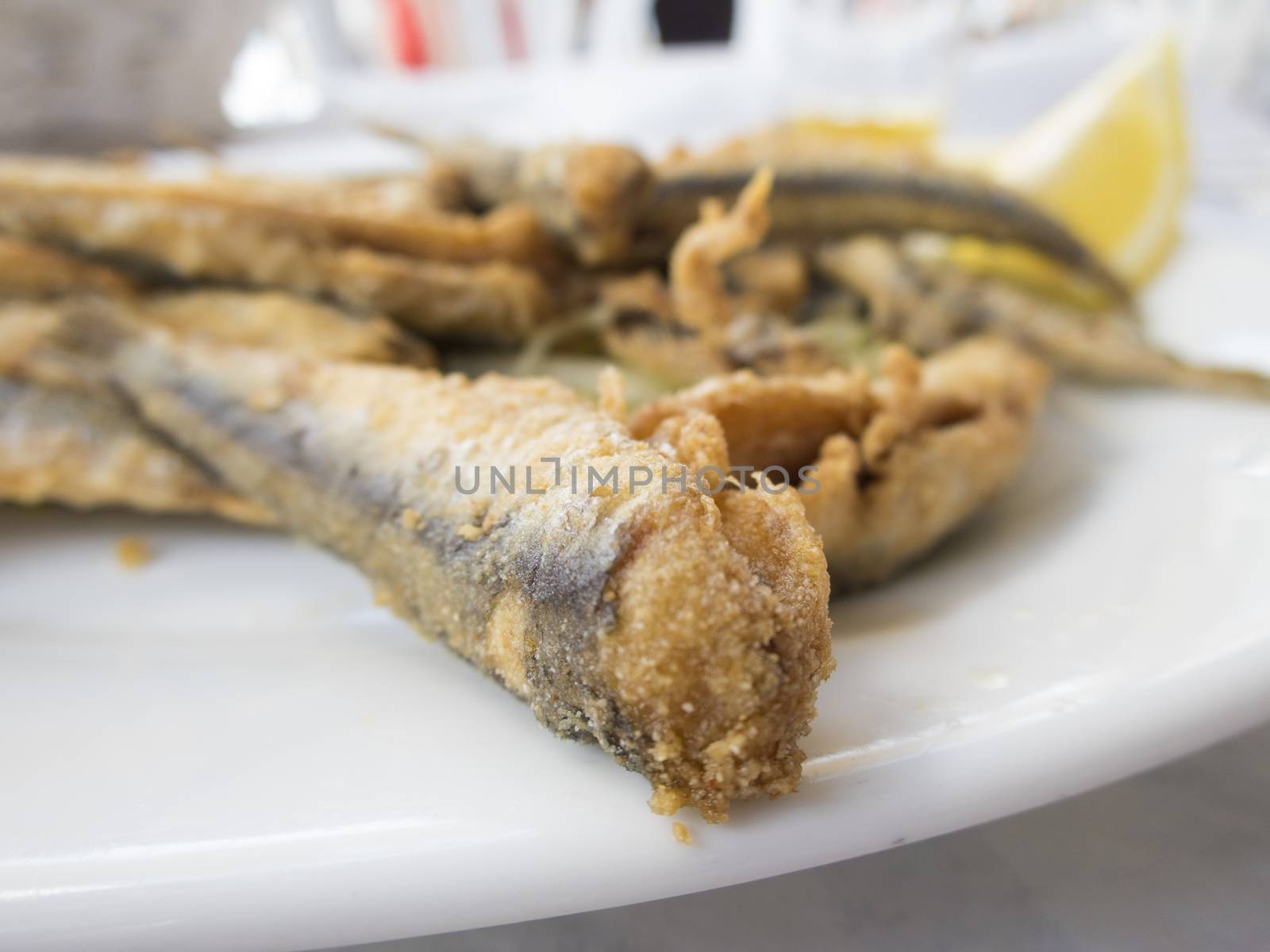 typical spanish fried sardines dish on white paper tablecloth restaurant