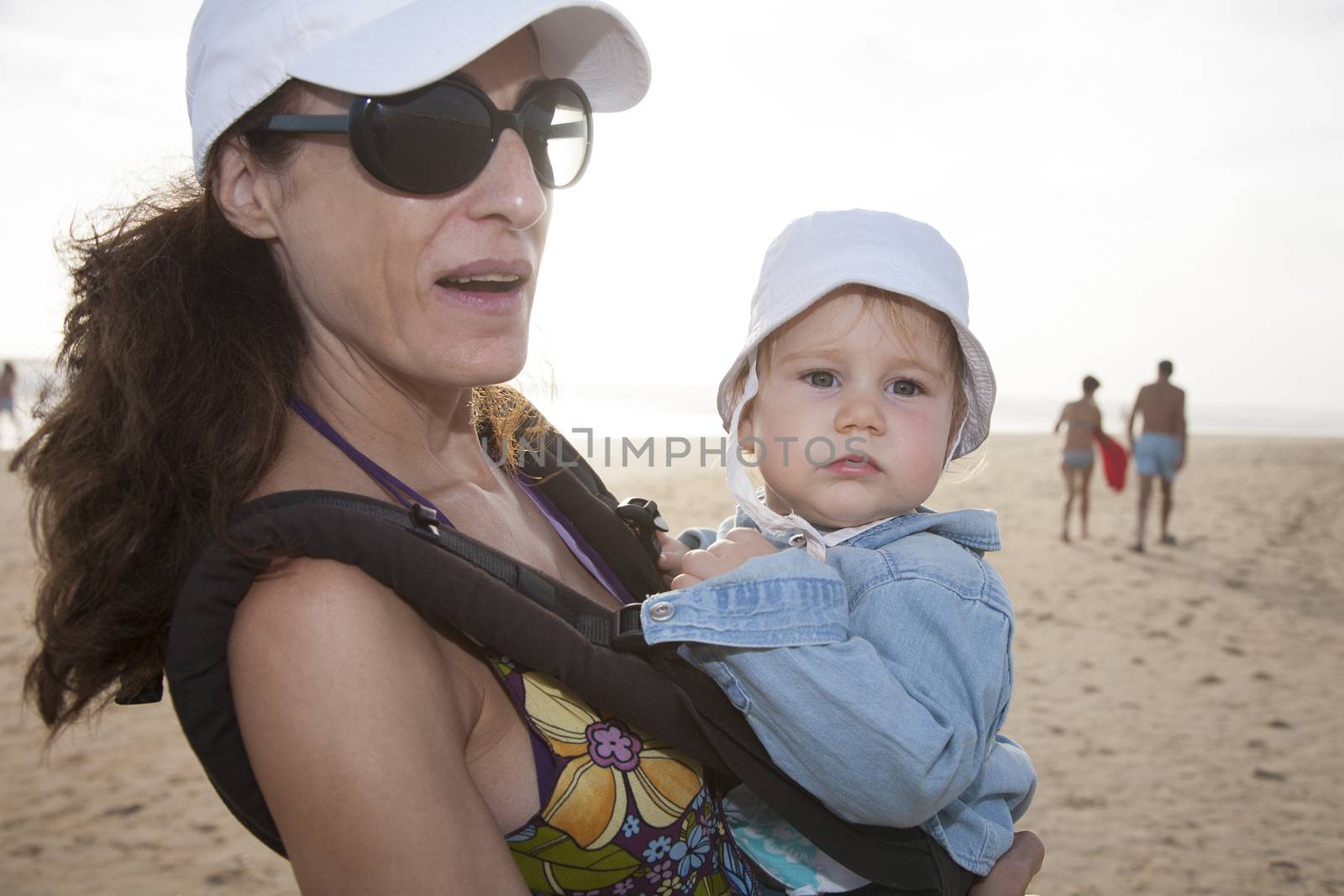 mom and baby in rucksack at beach by quintanilla