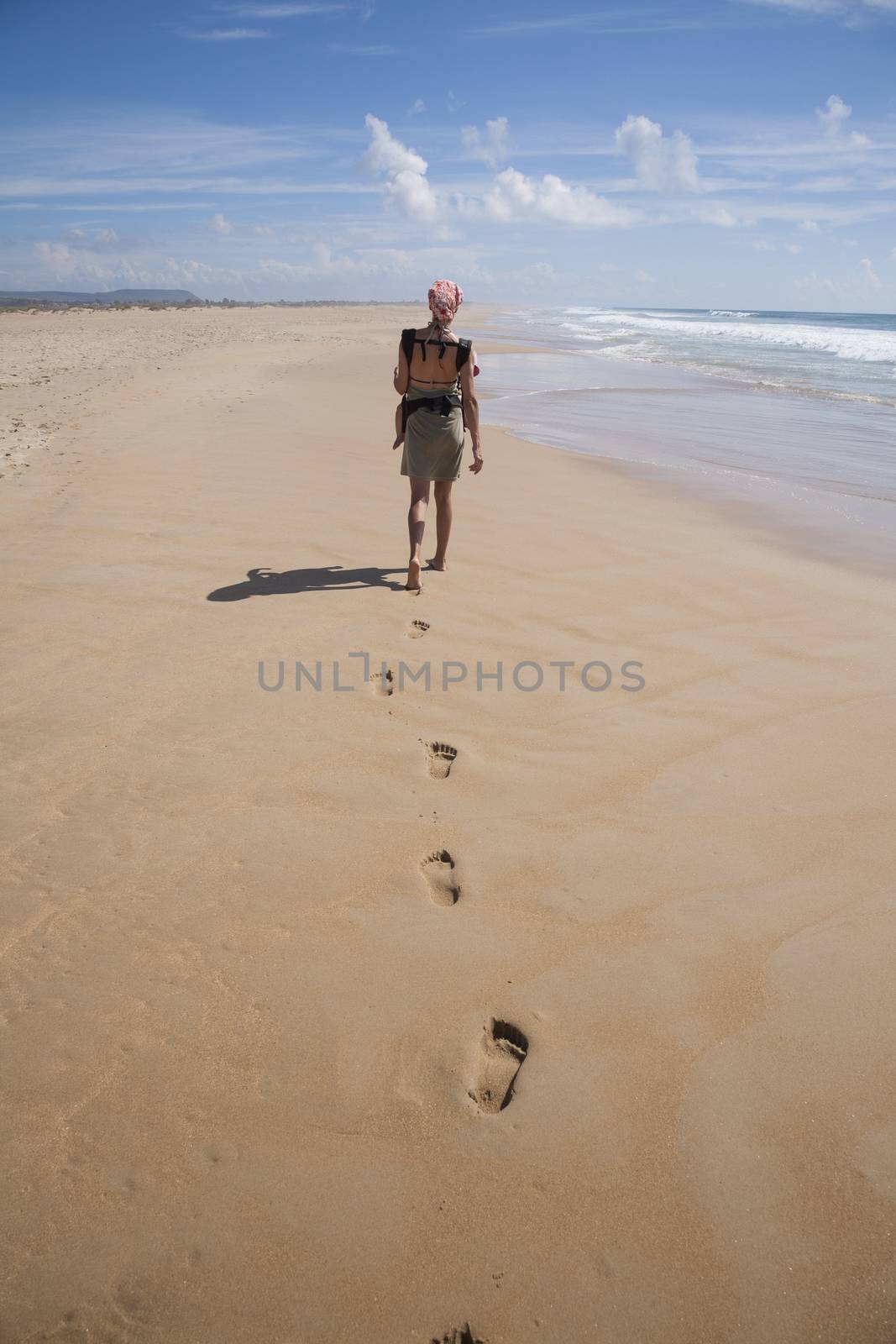 woman with baby rucksack at beach by quintanilla