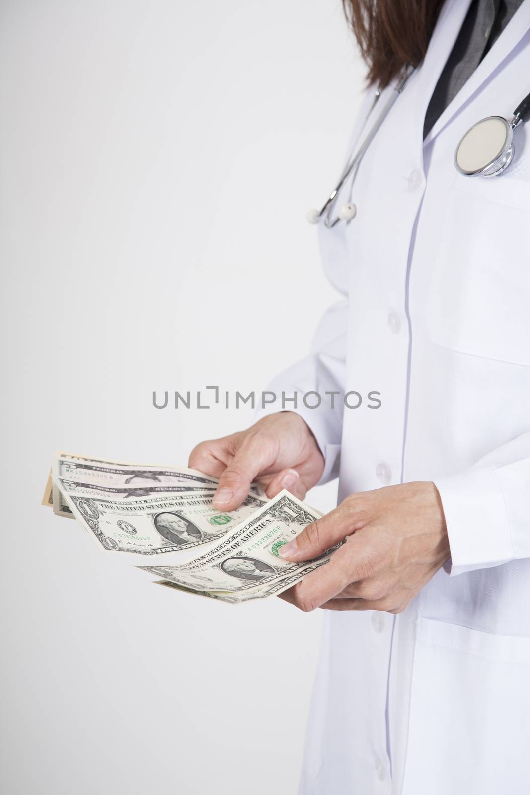 woman doctor hands with white gown and stethoscope counting wad of dollar banknotes isolated over white background