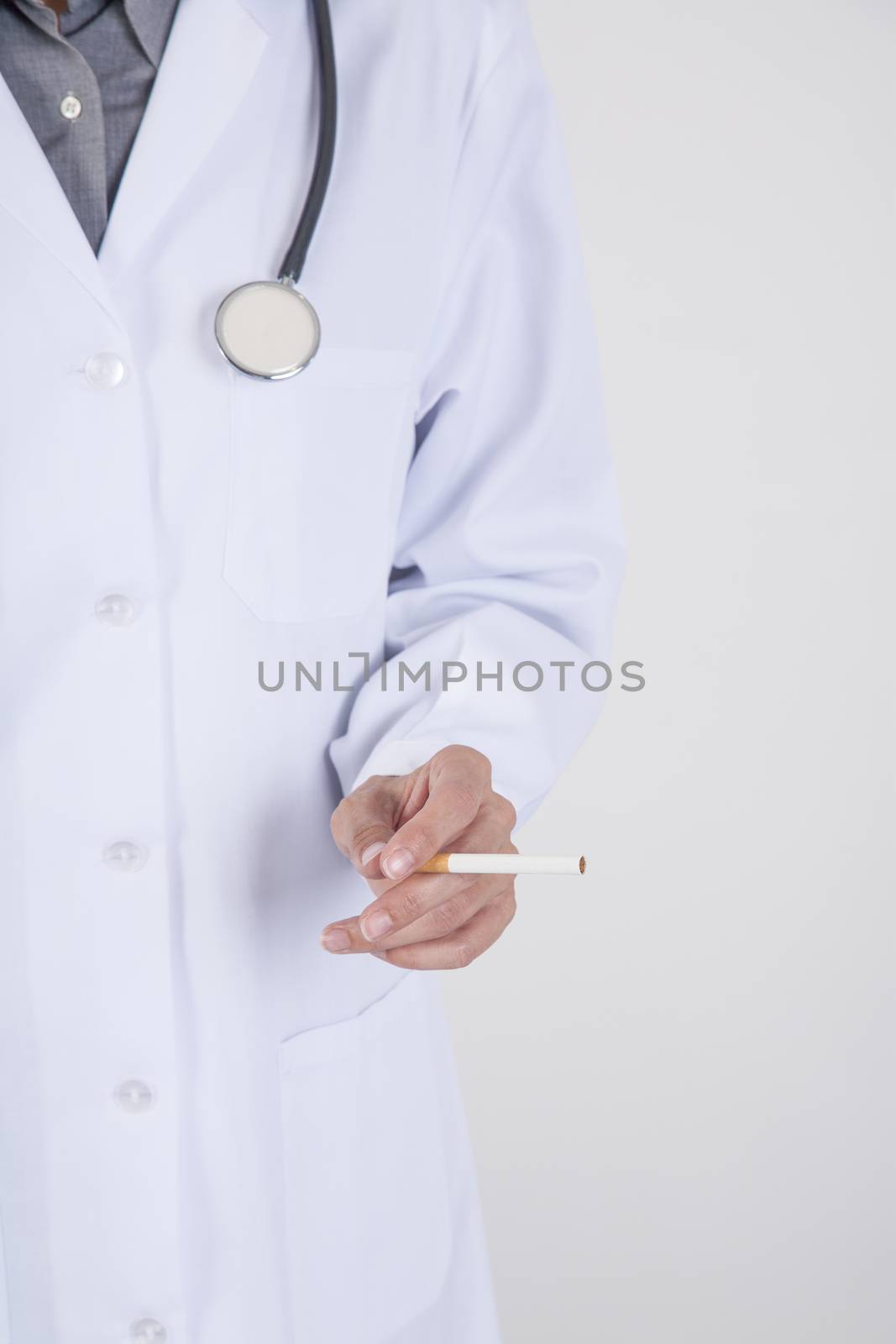 woman doctor with white gown and stethoscope with a cigarette tobacco in her hand over white background
