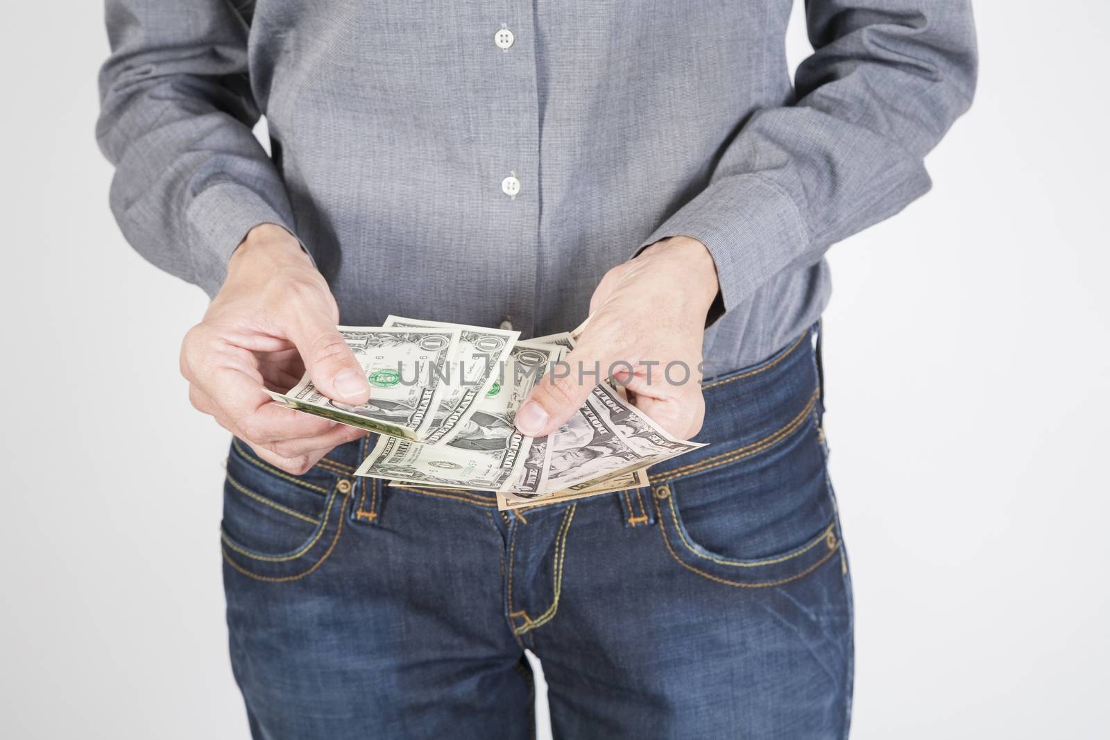 woman blue jeans trousers and grey shirt counting currency money cash one five ten and twenty dollar banknotes in her hands isolated over white background