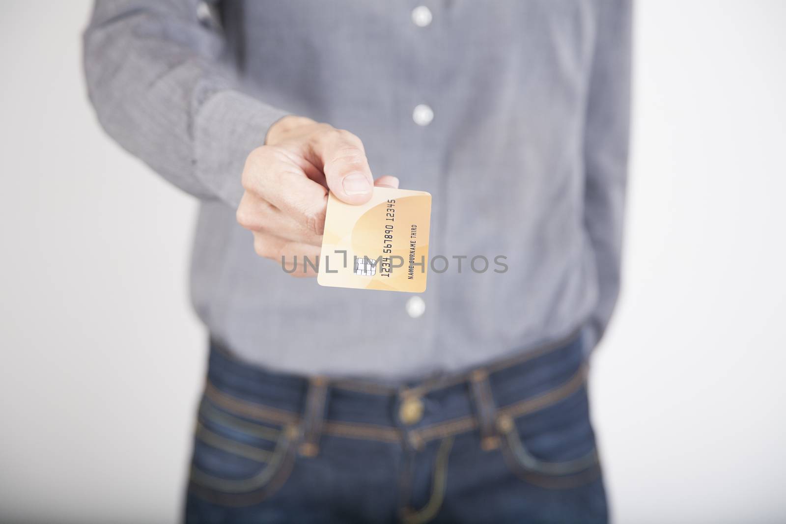 woman blue jeans trousers and grey shirt offering made up fiction credit card in her hands isolated over white background