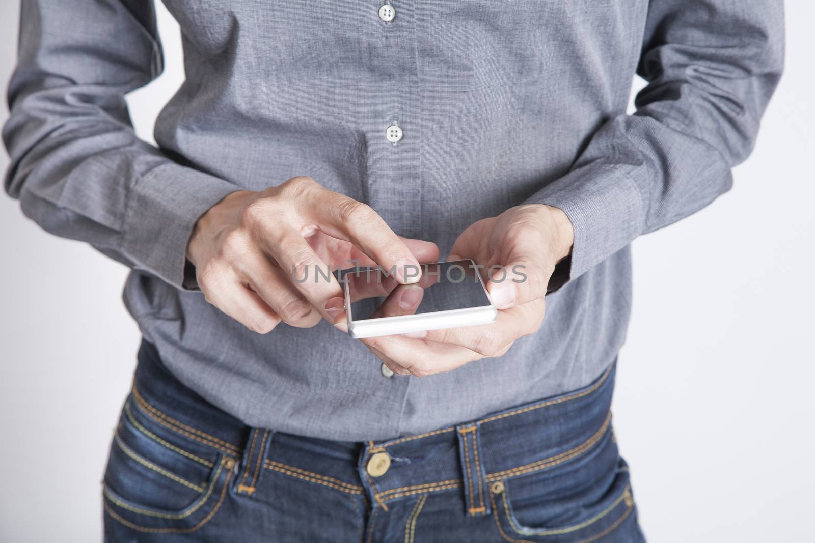 woman blue jeans trousers and grey shirt with mobile phone smartphone blank screen in her hand isolated over white background