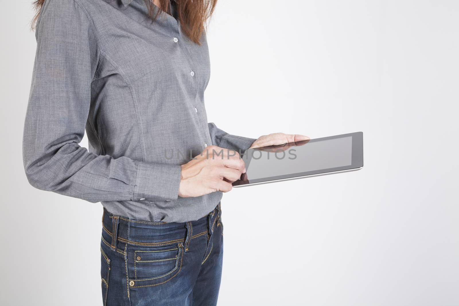 woman blue jeans trousers and grey shirt with digital tablet blank screen in her hand isolated over white background