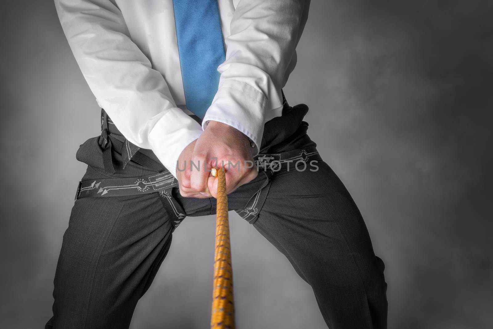 Image of a businessman hanging on a climbing rope