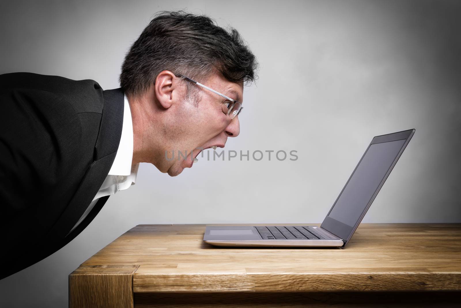 Man sitting at the table and screaming at his laptop