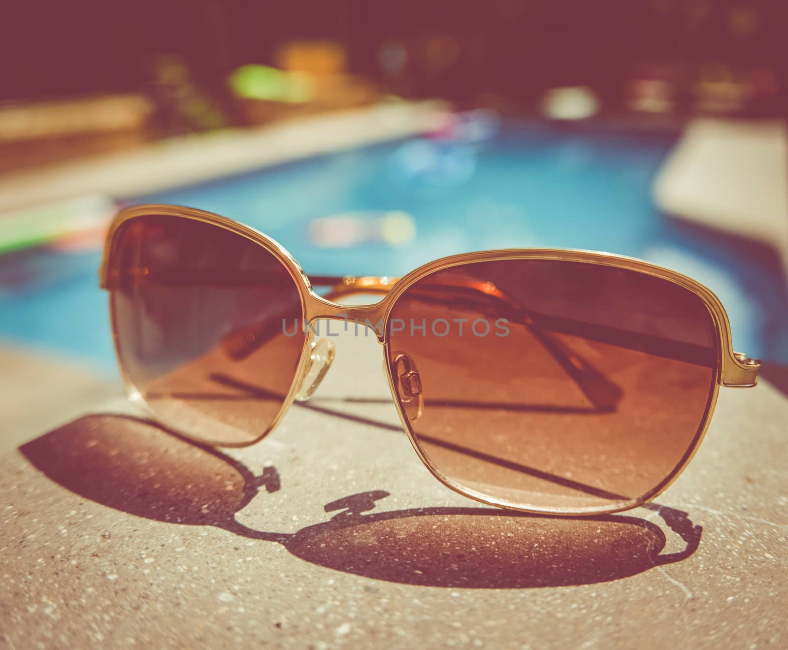 Retro Style Image Of Sunglasses Beside A Swimming Pool