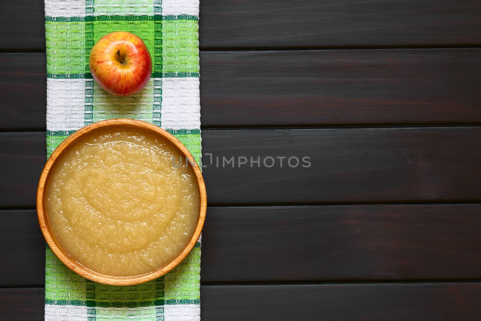 Homemade apple sauce in wooden bowl, photographed overhead on dark wood with natural light