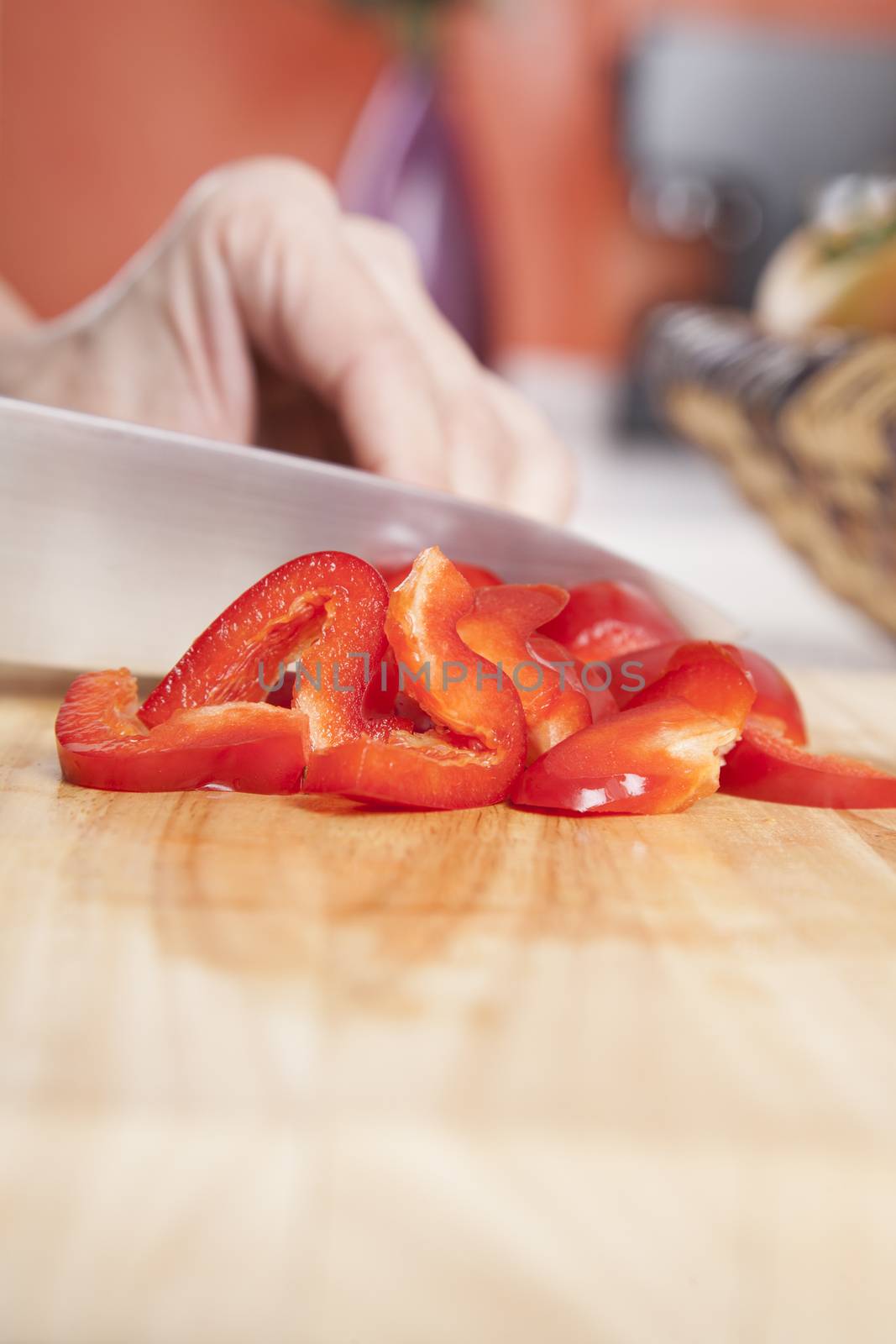 woman hands cutting red fresh pepper slices on brown wood plank white worktop