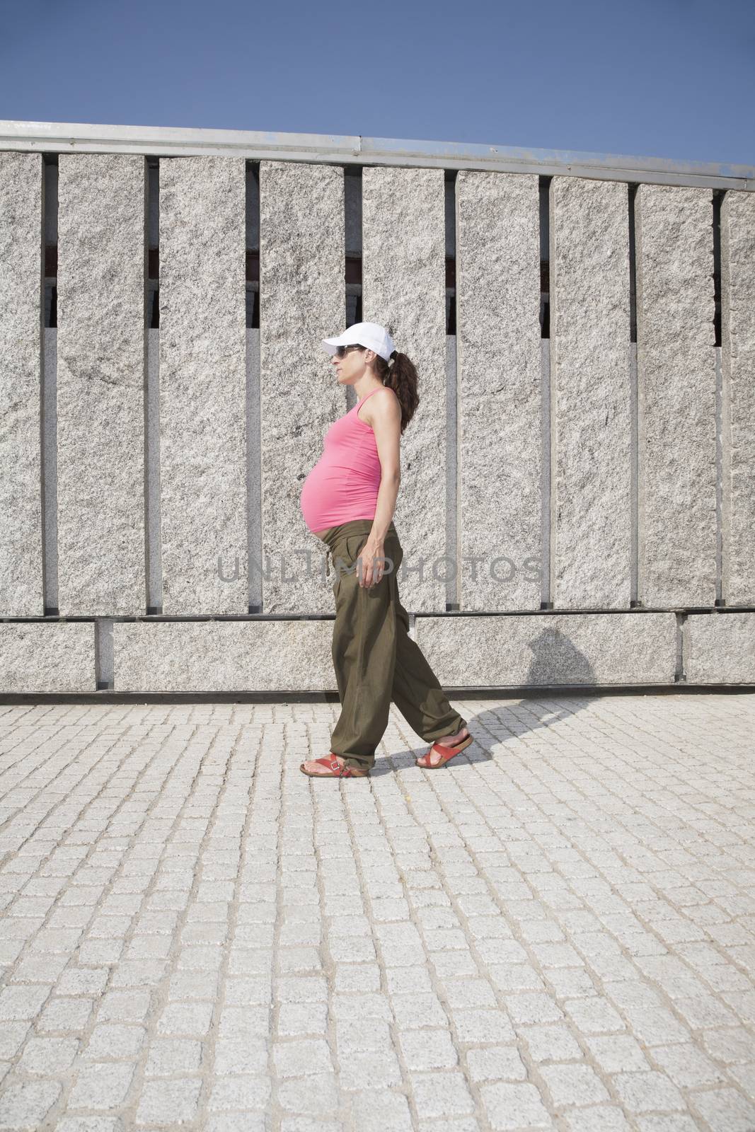 pregnant woman with pink shirt walking granite wall