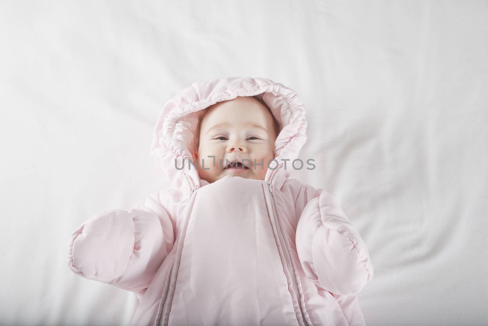 smiling baby face wrapped in pink snowsuit by quintanilla