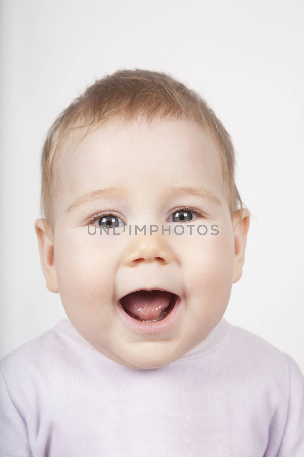 portrait of eight months age blonde lovely cute baby pink velvet onesie open mouth shout scream smiling happy face isolated on white