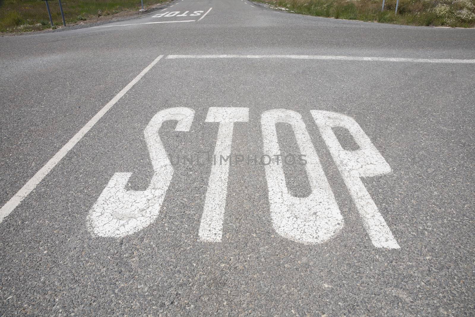 crossroads with stop symbol text painted on asphalt in rural road next to Madrid Spain Europe