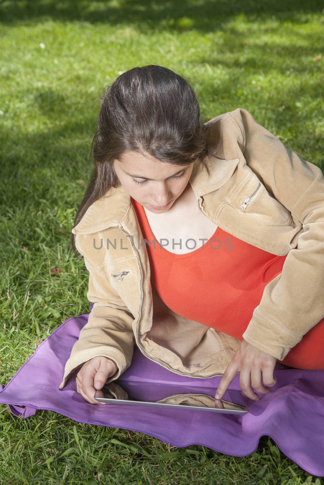 pregnant young woman with orange shirt touching tablet at a park in Madrid Spain Europe