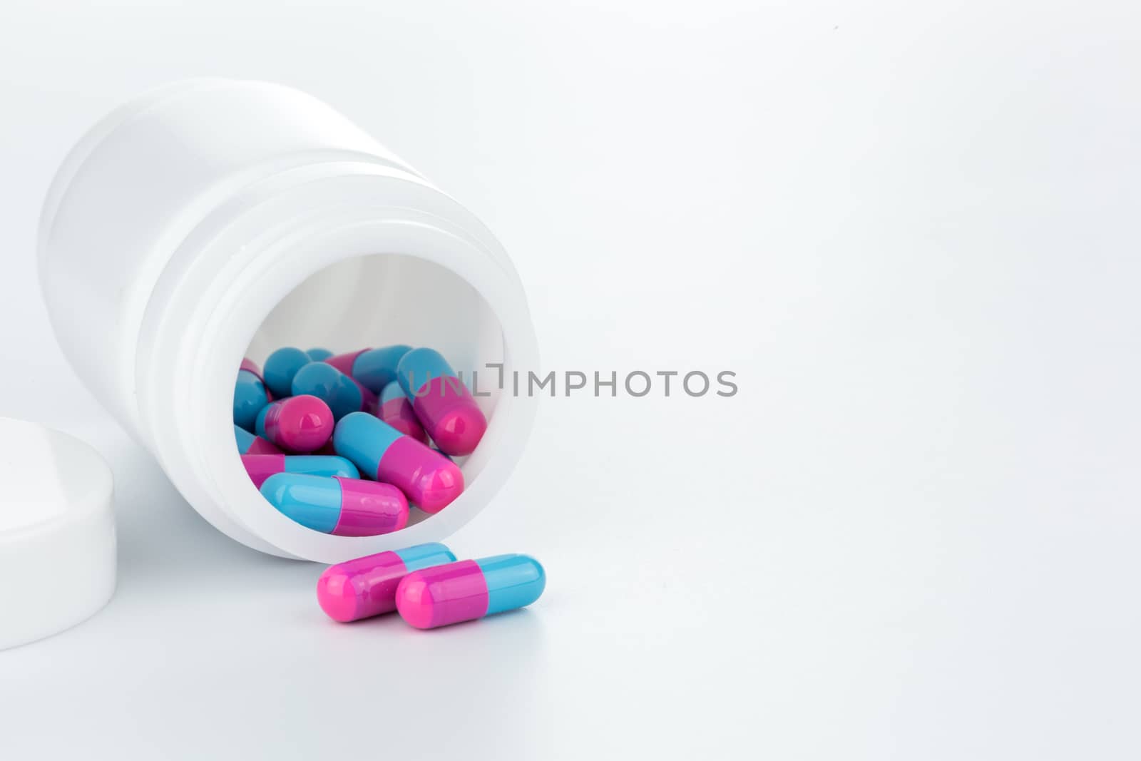 skyblue and pink pills an pill bottle on white background
 by urubank