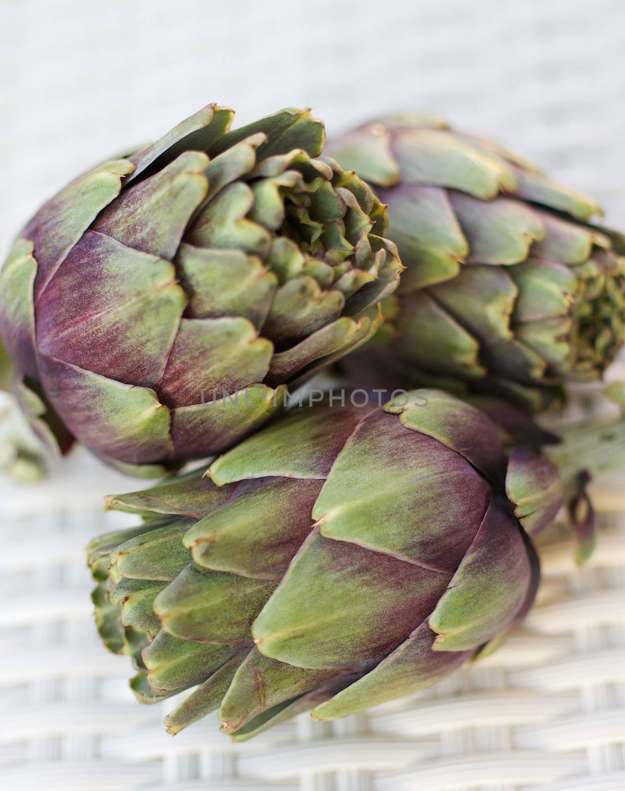 Arrangement of Three Ripe Crunchy Artichokes closeup on Wicker background. Selective Focus