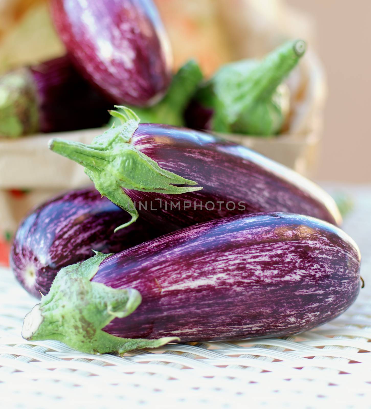 Heap of Fresh Raw Striped Eggplants closeup on Wicker background. Selective Focus