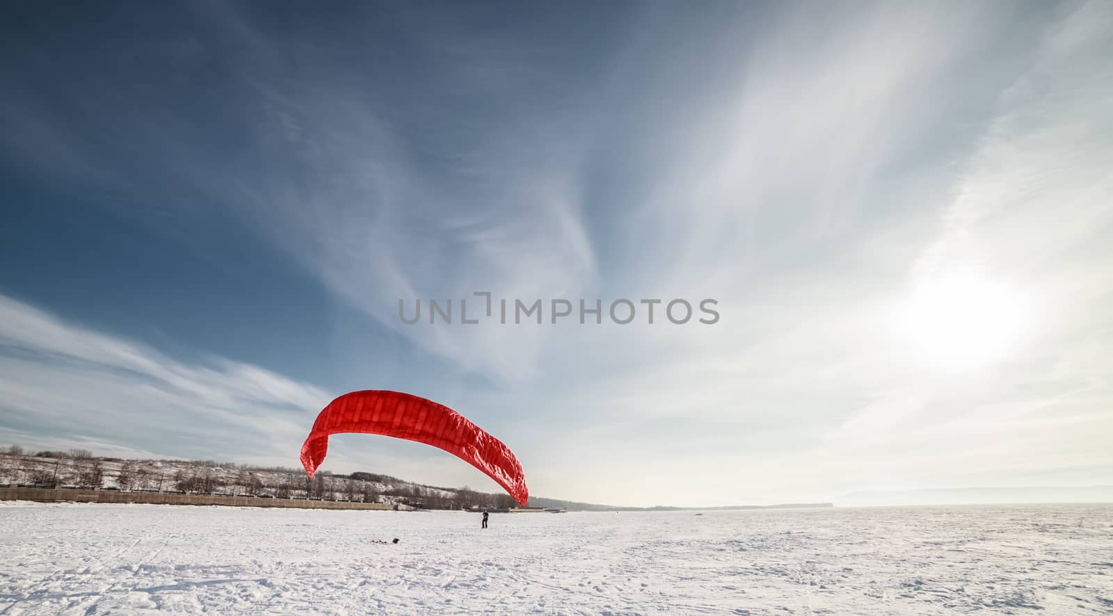 Kite surfer being pulled by his kite across the snow