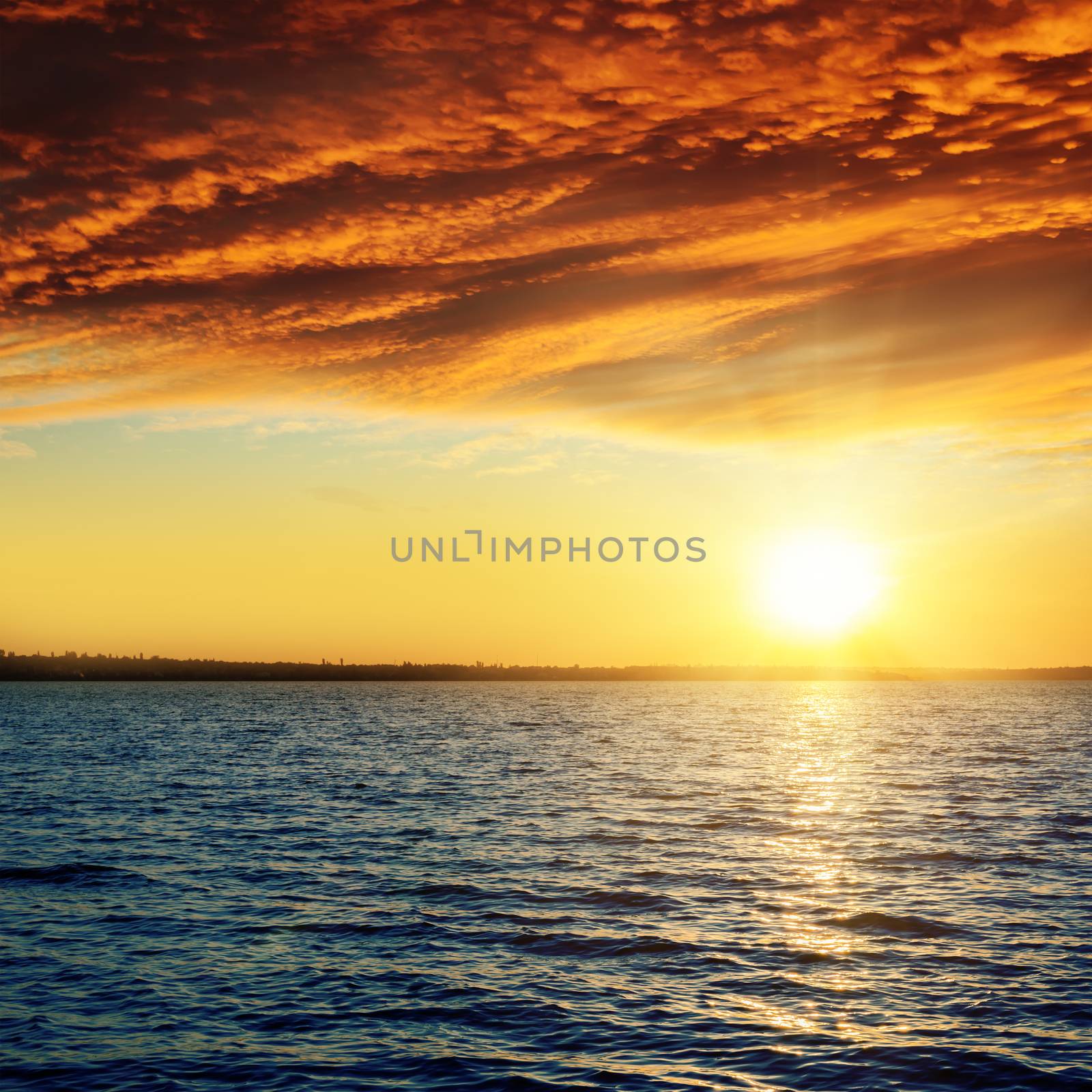 good red sunset over darken water by mycola