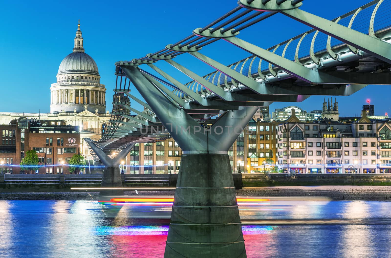 LONDON - JUNE 15, 2015: City night skyline with St Paul Cathedral and Millennium Bridge. London attracts 50 million people annually.