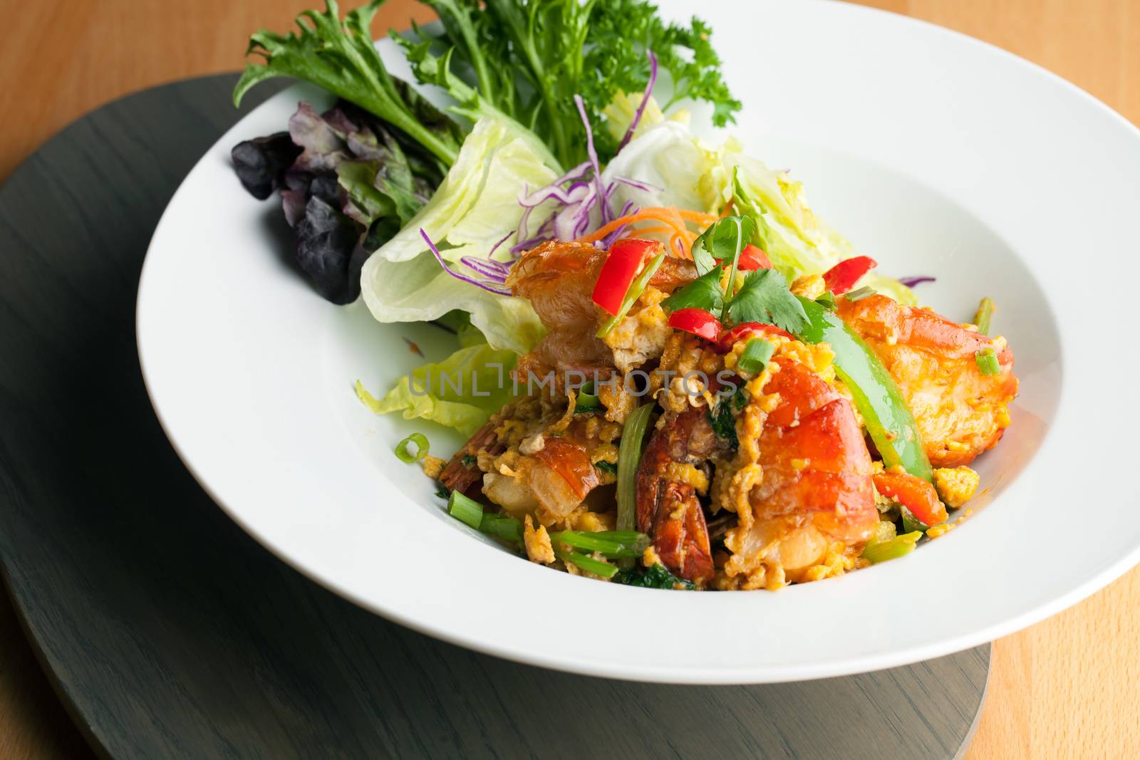 Thai jumbo shrimp salad on a round white plate. Shallow depth of field.