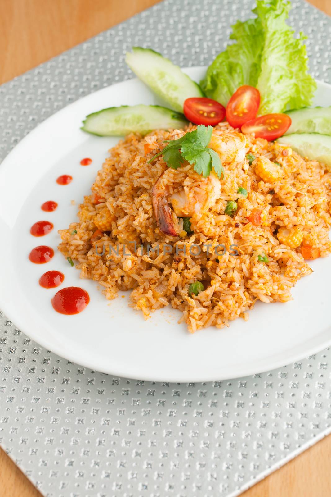 Sriracha shrimp fried rice dish with garnish dots of siracha sauce.