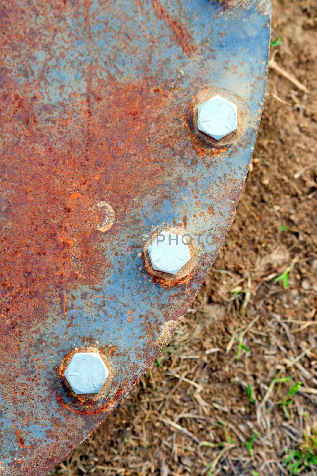 Rusted metal and hex bolts hold down industiral pipe cover