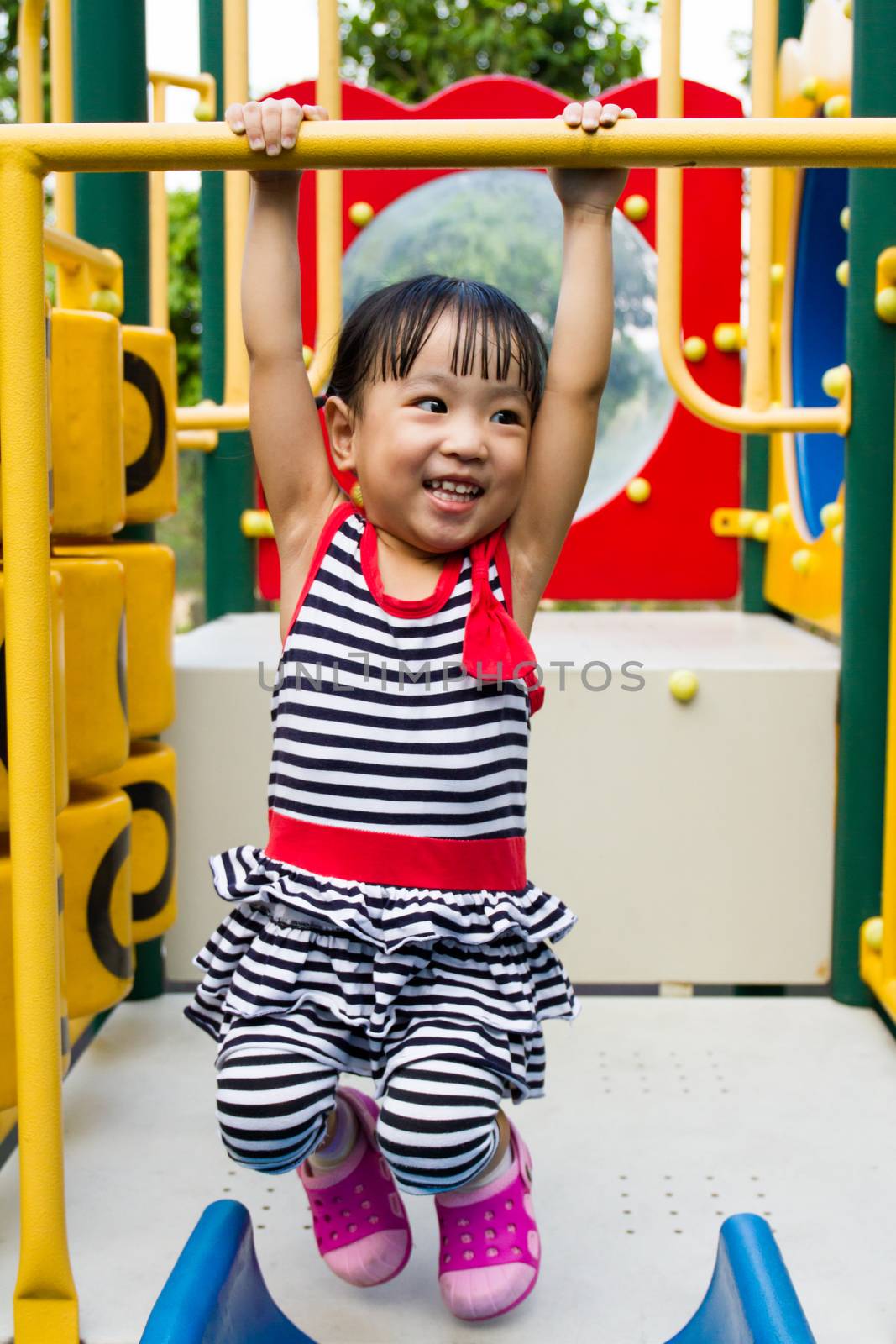 Asian Chinese little girl hanging on outdoor playground