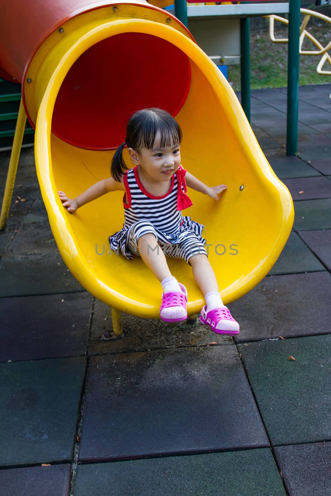 Asian kid sliding on Playground by kiankhoon