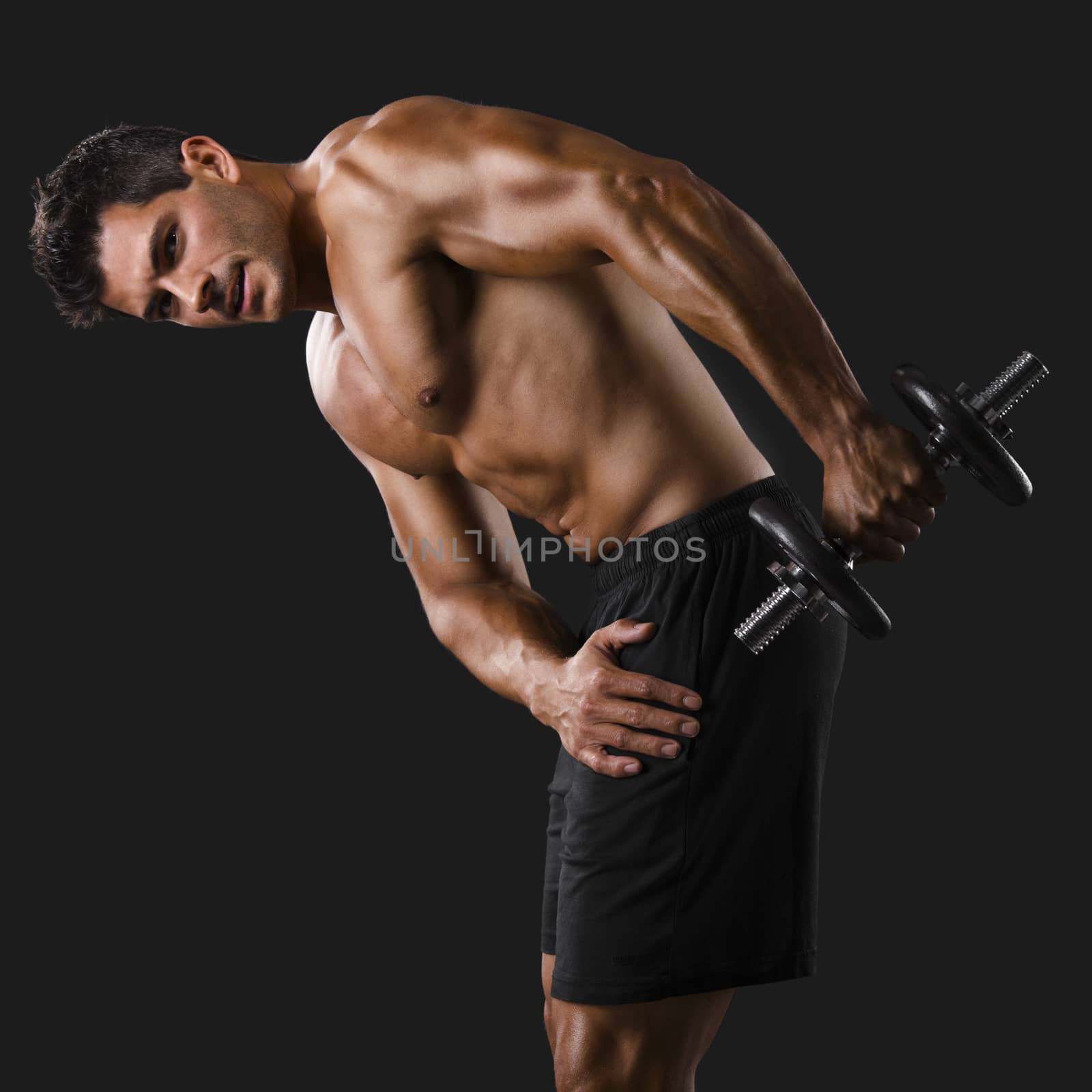 Portrait of a muscular man lifting weights against a dark background