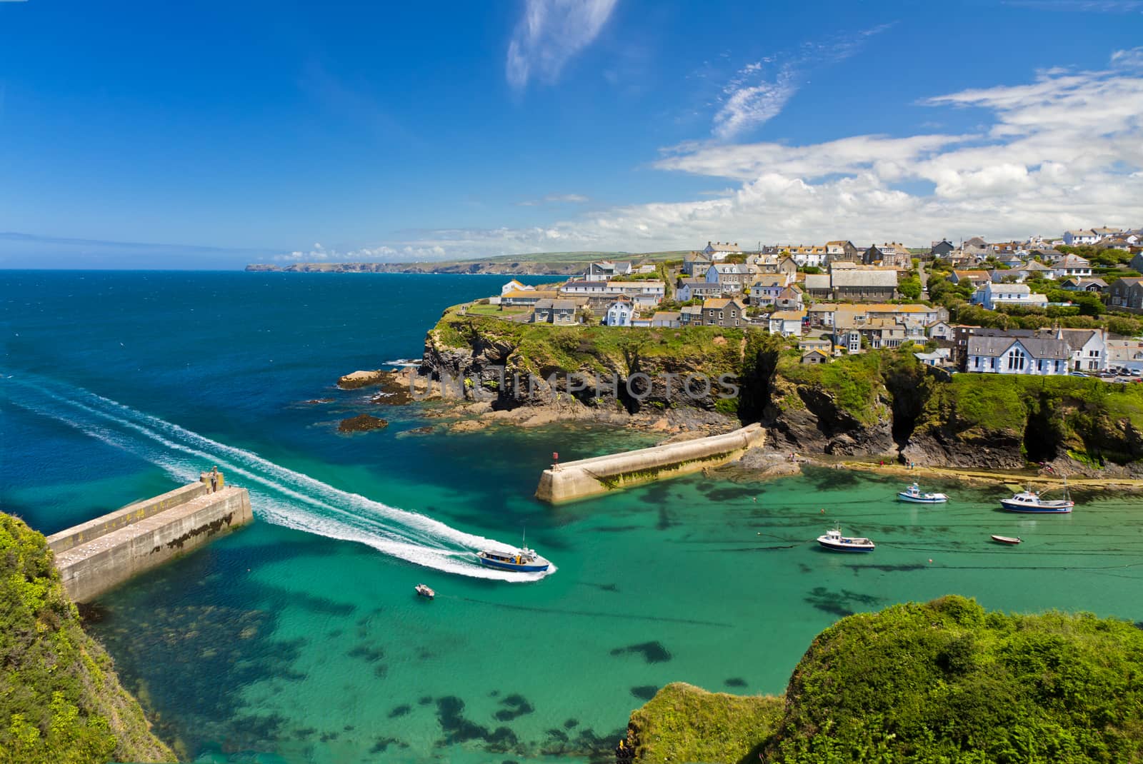 Cove and harbour of Port Isaac with arriving ship, Cornwall, England